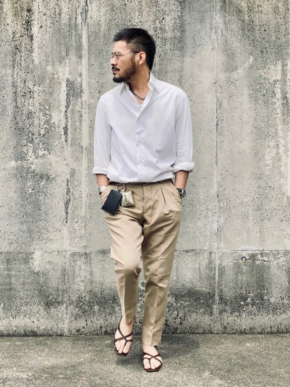 ベージュ系のスラックス、ブラウン系のサンダル、ブラック系のアナログ腕時計を着用したメンズの春コーディネートの1枚目の写真