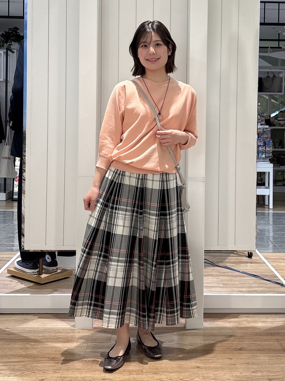 レッド系のスカート、オレンジ系のニット/セーター、シルバー系のショルダーバッグを着用したレディースの春コーディネートの1枚目の写真