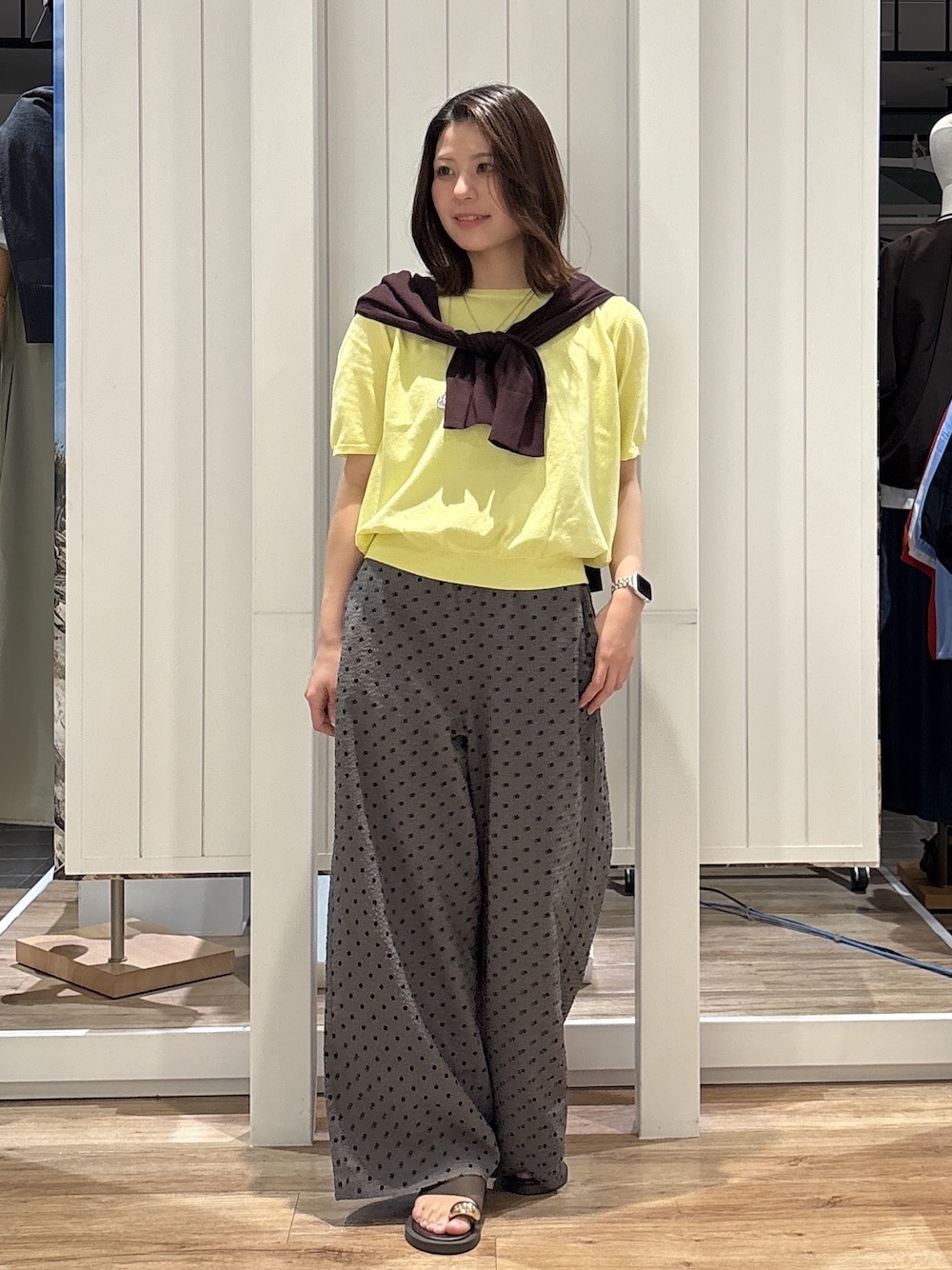 イエロー系のニット/セーター、グレー系のその他パンツ、ブラウン系のサンダルを着用したレディースの夏コーディネートの1枚目の写真