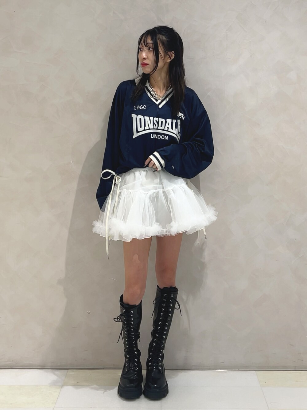 ブルー系のTシャツ/カットソー、ホワイト系のスカート、ブラック系のブーツを着用したレディースの秋コーディネートの1枚目の写真