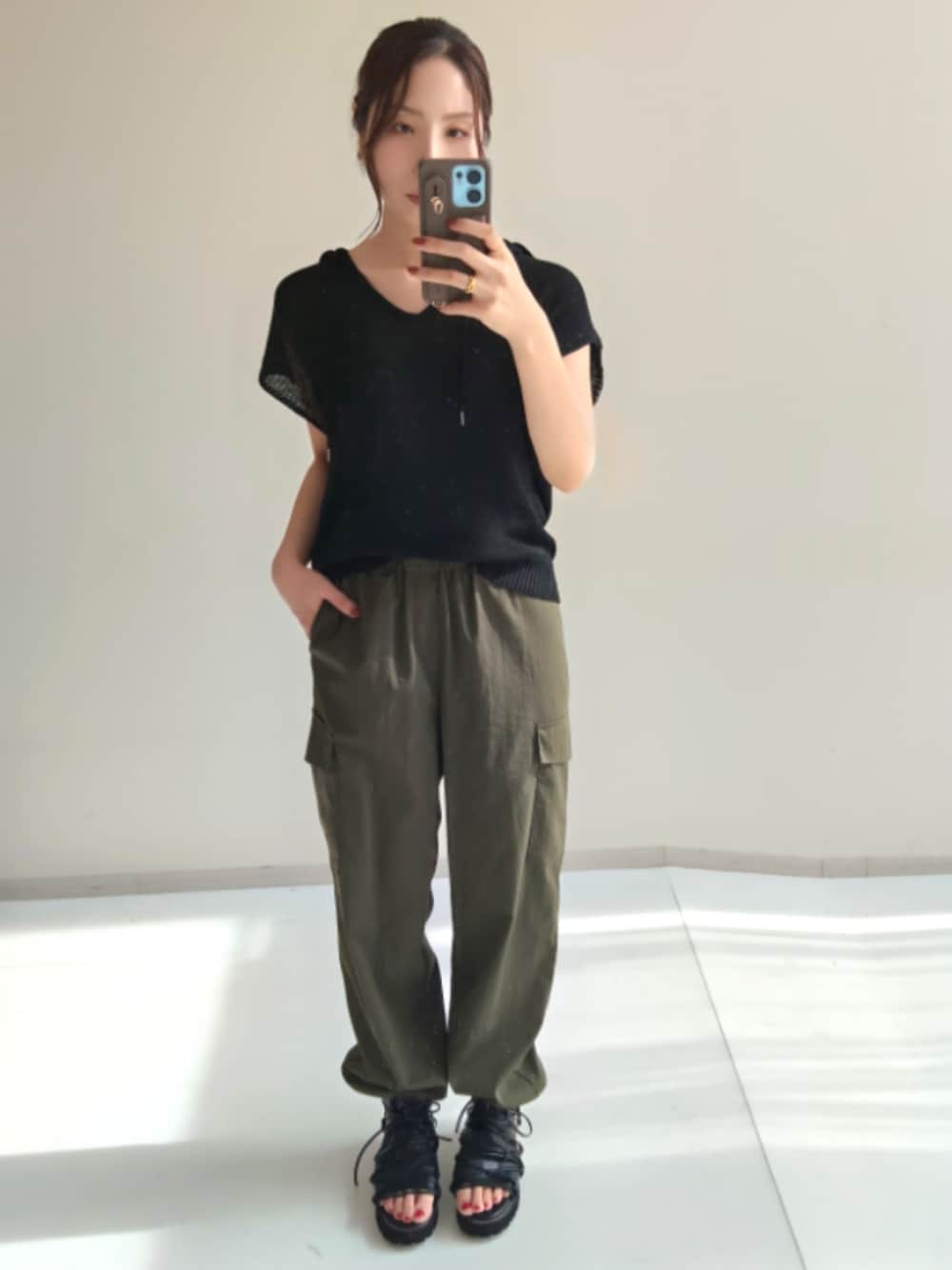 グリーン系のカーゴパンツ、グリーン系のカーゴパンツ、ブラック系のニット/セーターを着用したレディースの夏コーディネートの1枚目の写真