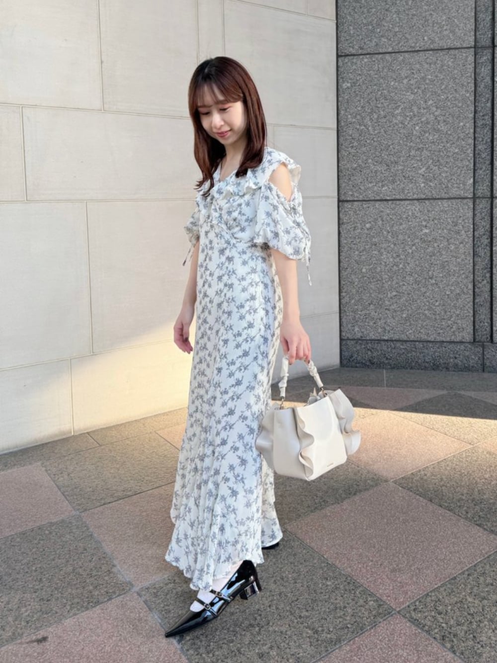 ホワイト系のワンピース、ブラック系のパンプス、ホワイト系のハンドバッグを着用したレディースの春コーディネートの1枚目の写真