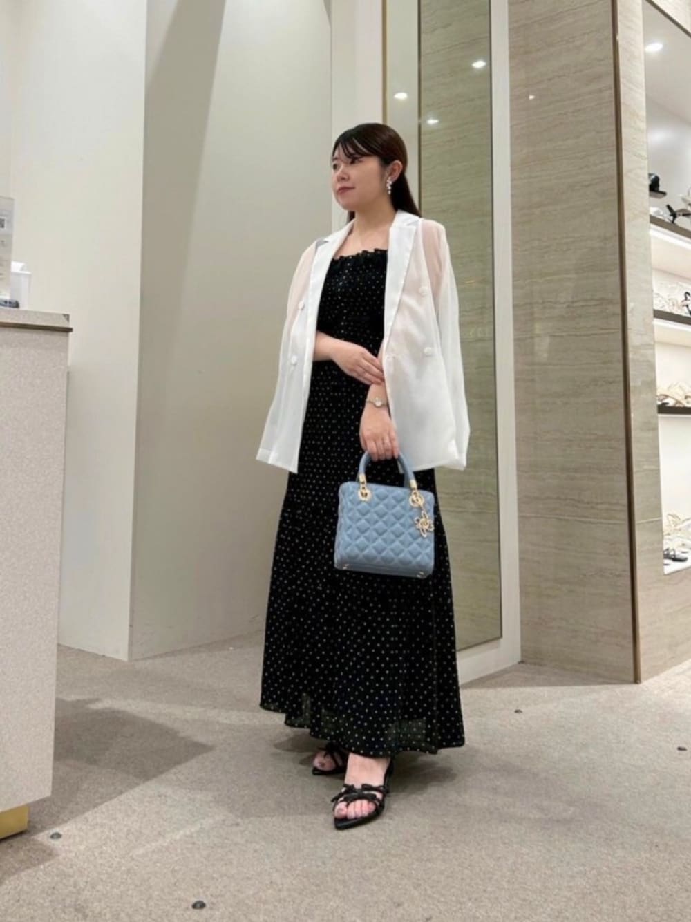 ブラック系のサンダル、ブルー系のハンドバッグ、ホワイト系のブルゾンを着用したレディースの春コーディネートの1枚目の写真