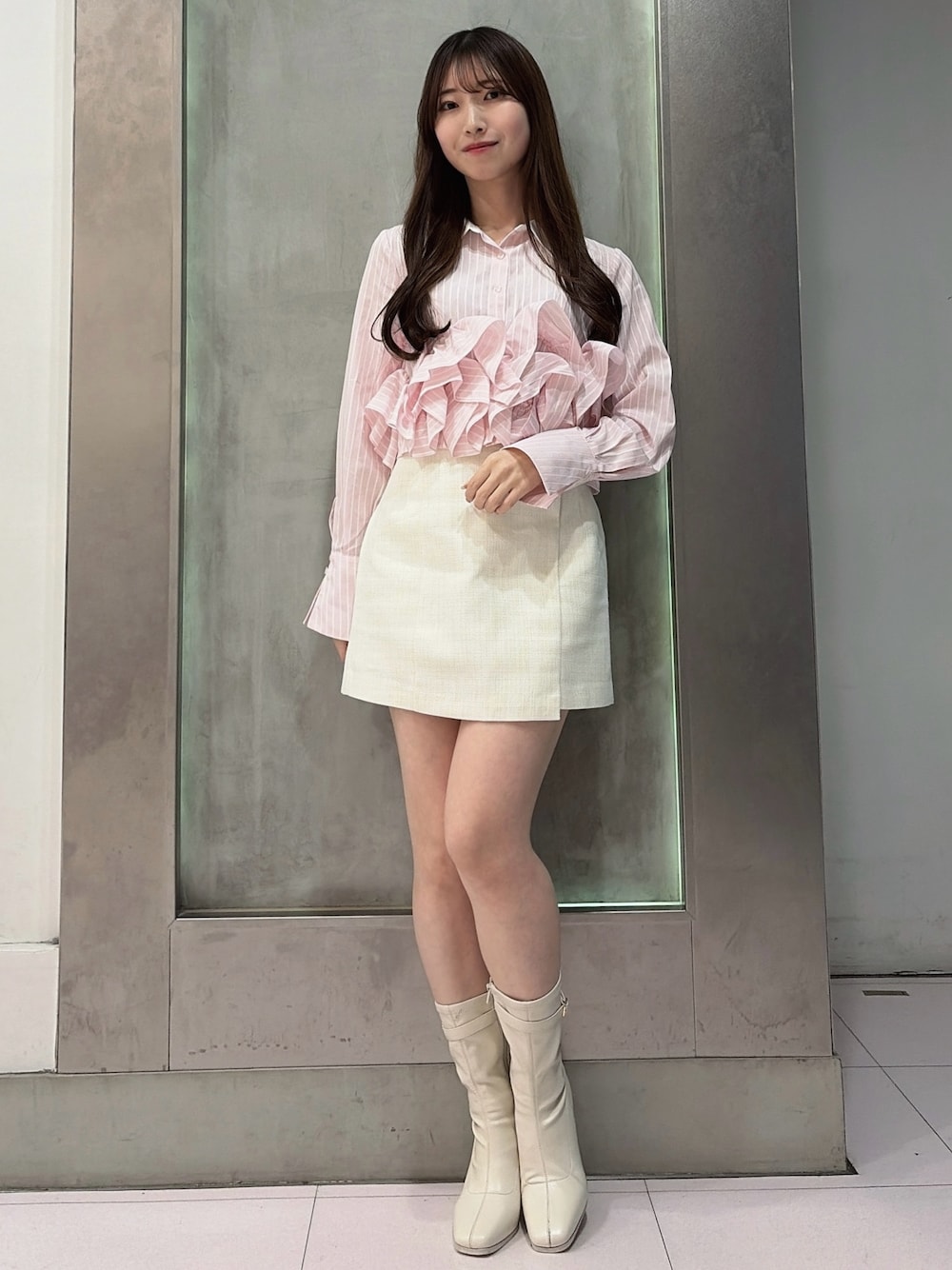 ピンク系のシャツ/ブラウス、ホワイト系のスカート、ホワイト系のブーツを着用したレディースの春コーディネートの1枚目の写真