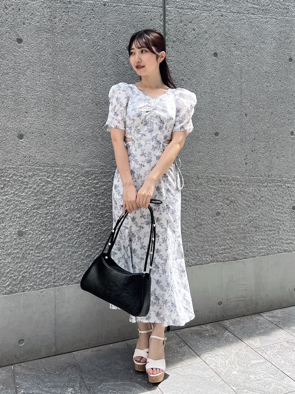ホワイト系のワンピース、ブラック系のハンドバッグ、ホワイト系のサンダルを着用したレディースの夏コーディネートの1枚目の写真