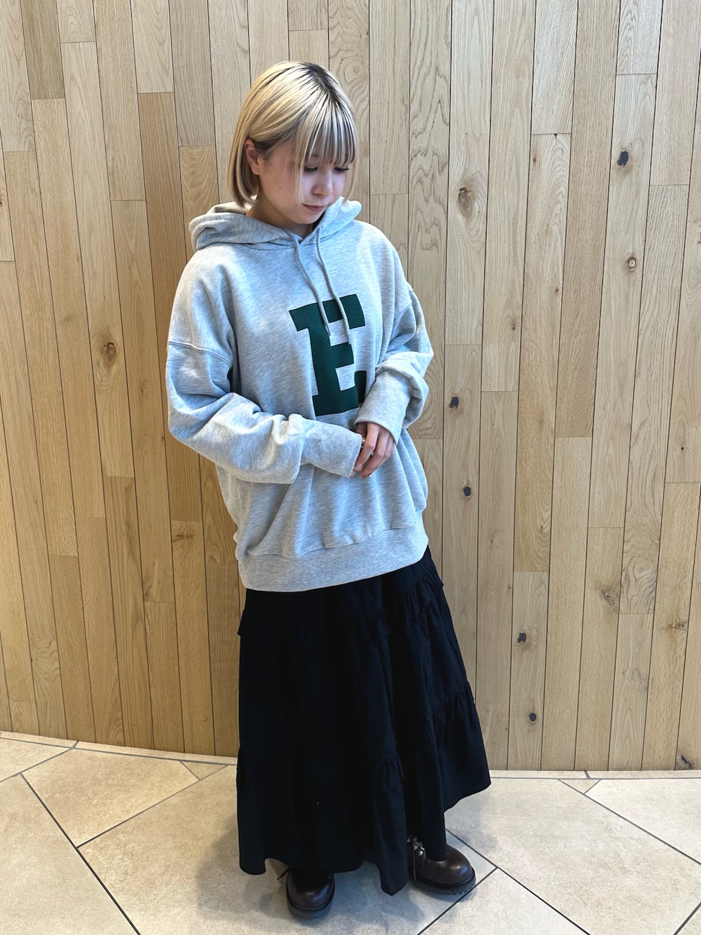 グレー系のTシャツ/カットソー、ブラック系のスカート、ブラウン系のブーツを着用したレディースの冬コーディネートの1枚目の写真