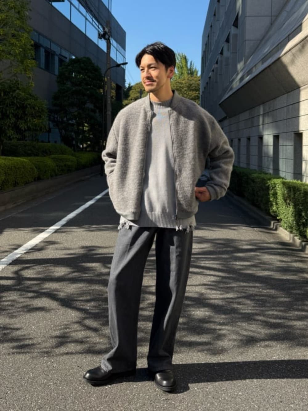 グレー系のブルゾン、グレー系のニット/セーター、グレー系のデニムパンツを着用したメンズの秋コーディネートの1枚目の写真