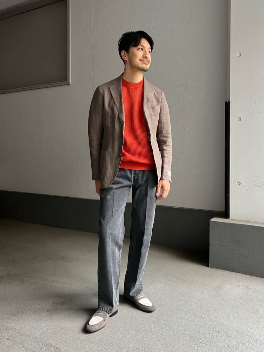 ブラウン系のテーラードジャケット、オレンジ系のTシャツ/カットソー、ブラック系のデニムパンツを着用したメンズの春コーディネートの1枚目の写真