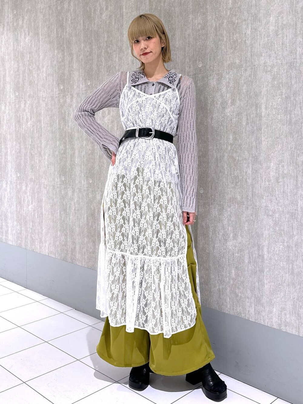 イエロー系のカーゴパンツ、グレー系のニット/セーター、ホワイト系のワンピースを着用したレディースの春コーディネートの1枚目の写真