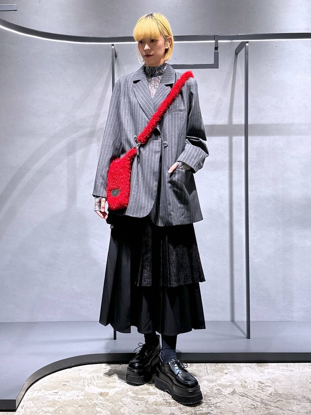 ブラック系のスカート、レッド系のショルダーバッグ、ブラック系のドレスシューズを着用したレディースの秋コーディネートの1枚目の写真