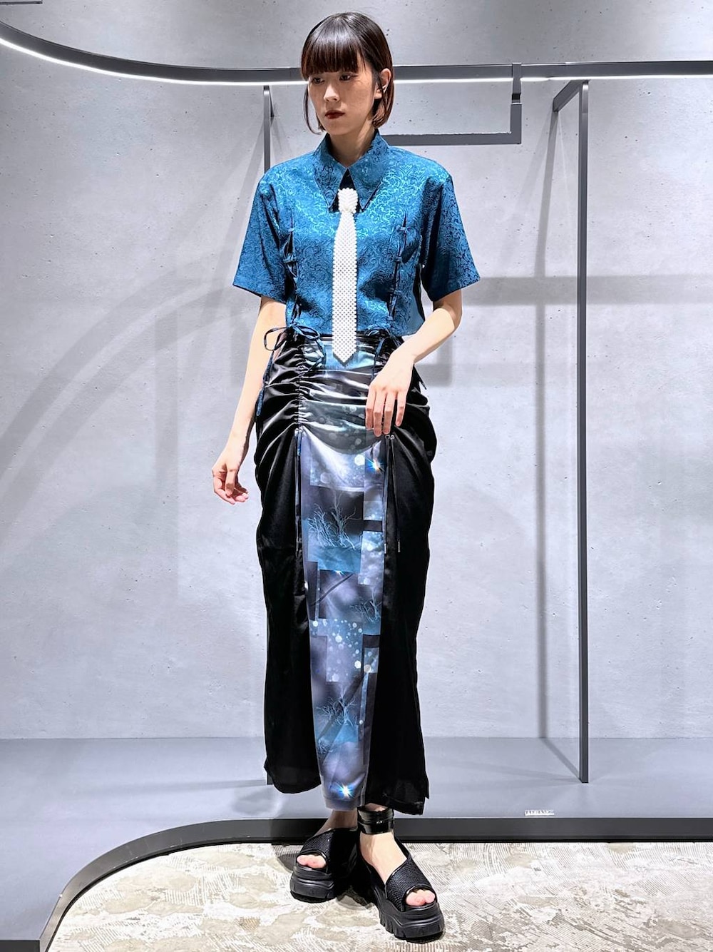 グリーン系のシャツ/ブラウス、ブラック系のサンダル、ブラック系のスカートを着用したレディースの夏コーディネートの1枚目の写真