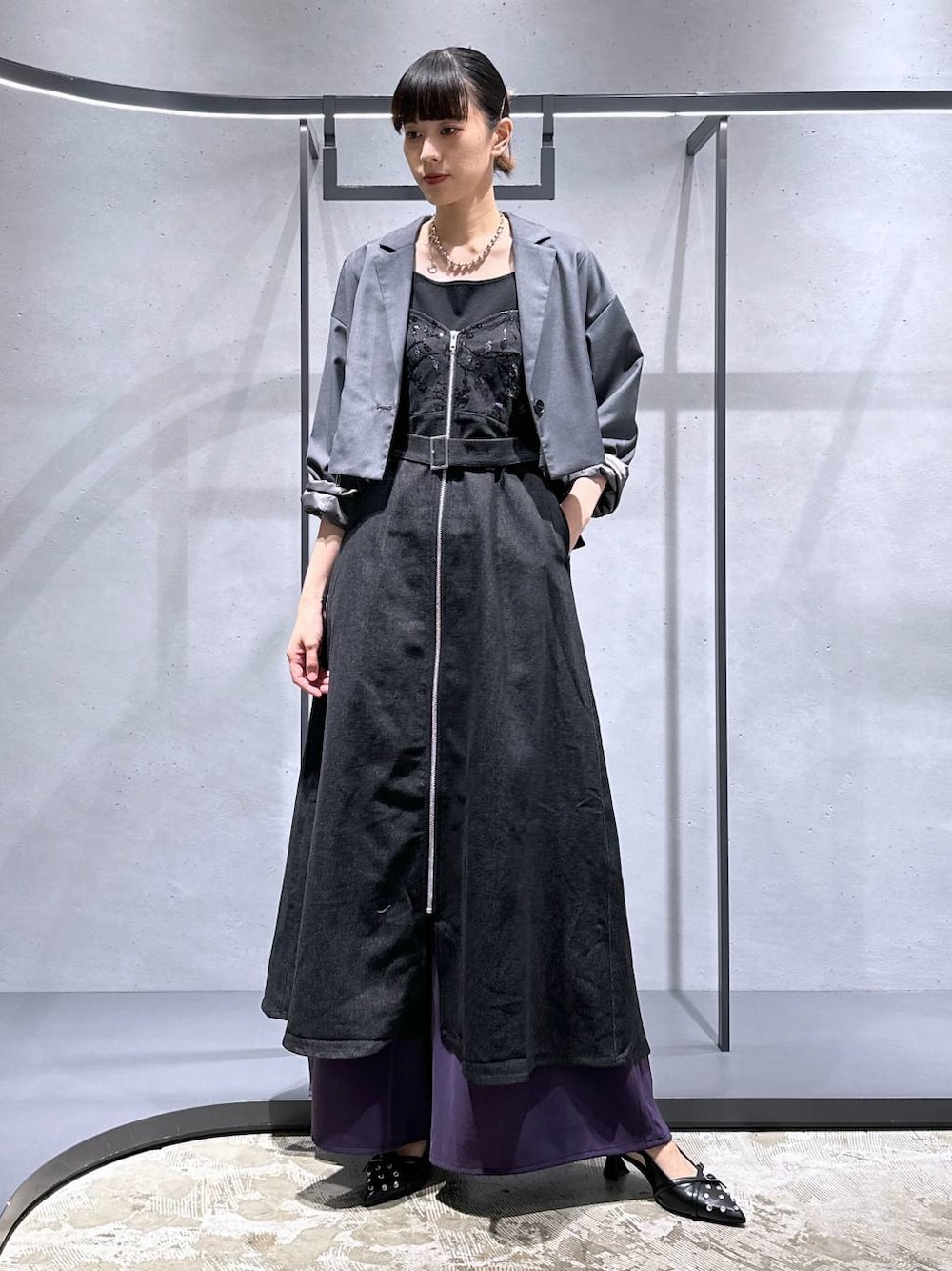 グレー系のテーラードジャケット、ブラック系のパンプス、パープル系のスラックスを着用したレディースの夏コーディネートの1枚目の写真