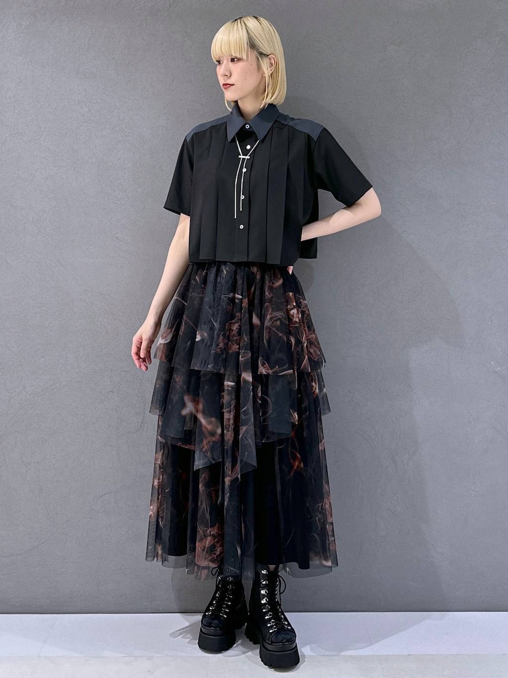 ブラック系のサンダル、オレンジ系のスカート、ブラック系のシャツ/ブラウスを着用したレディースの夏コーディネートの1枚目の写真