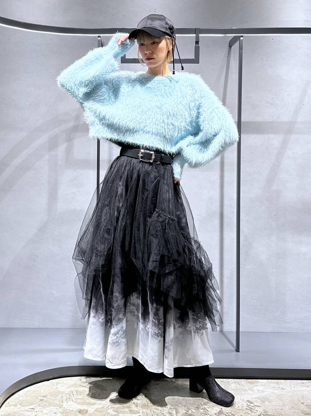 グリーン系のニット/セーター、ブラック系のブーツ、ブラック系のスカートを着用したレディースの冬コーディネートの1枚目の写真