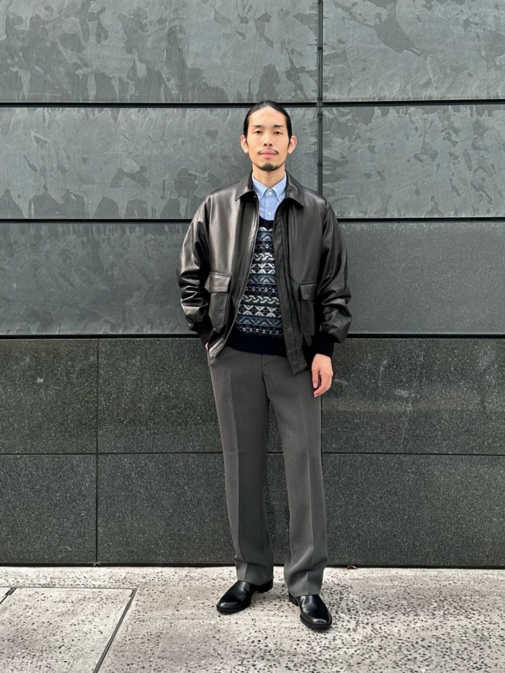 グレー系のスラックス、ブルー系のビジネスシャツ、ブラック系のブーツを着用したメンズの冬コーディネートの1枚目の写真