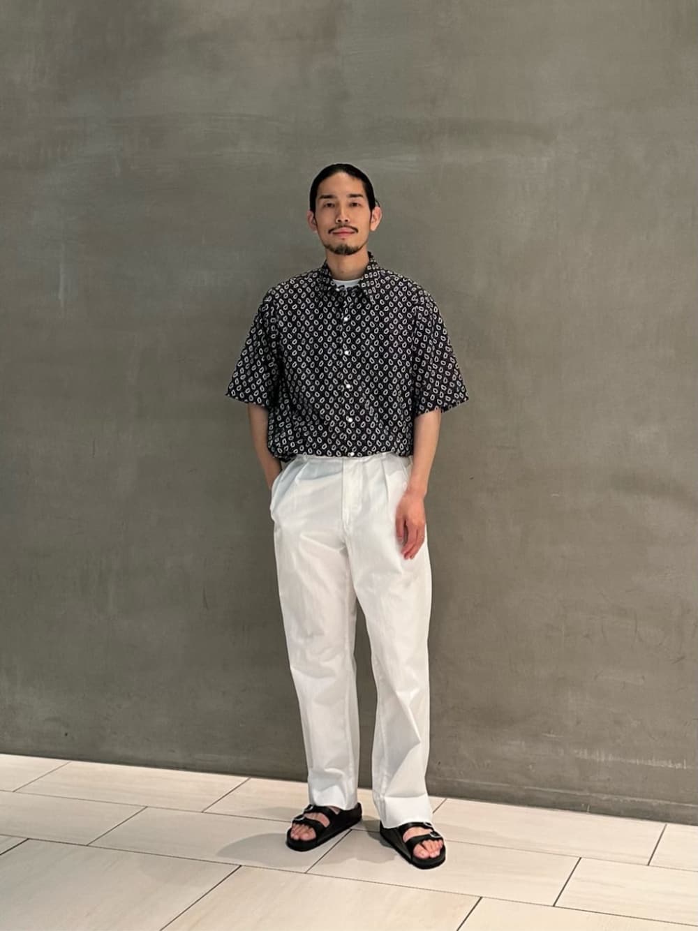 ホワイト系のTシャツ/カットソー、ホワイト系のチノパンツ、ブラック系のサンダルを着用したメンズの夏コーディネートの1枚目の写真