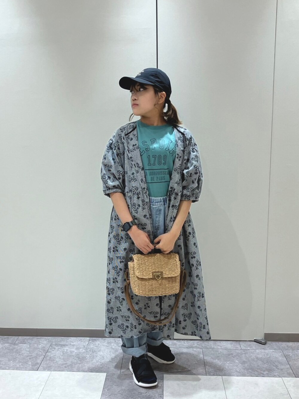 ホワイト系のハンドバッグ、グリーン系のTシャツ/カットソー、ブラック系のワンピースを着用したレディースの春コーディネートの1枚目の写真