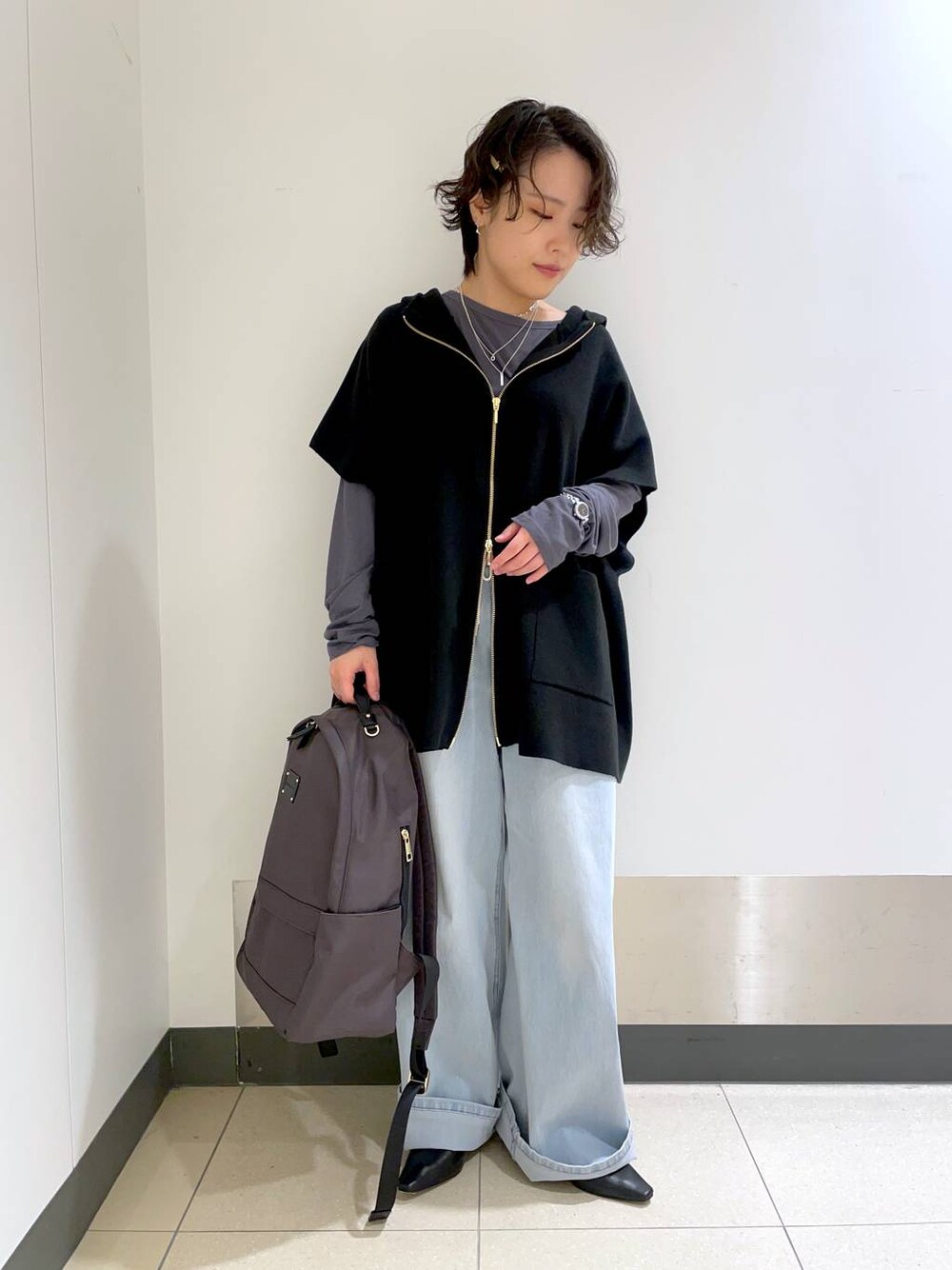 グレー系のバックパック/リュック、ブラック系のベスト、グレー系のTシャツ/カットソーを着用したレディースの冬コーディネートの1枚目の写真