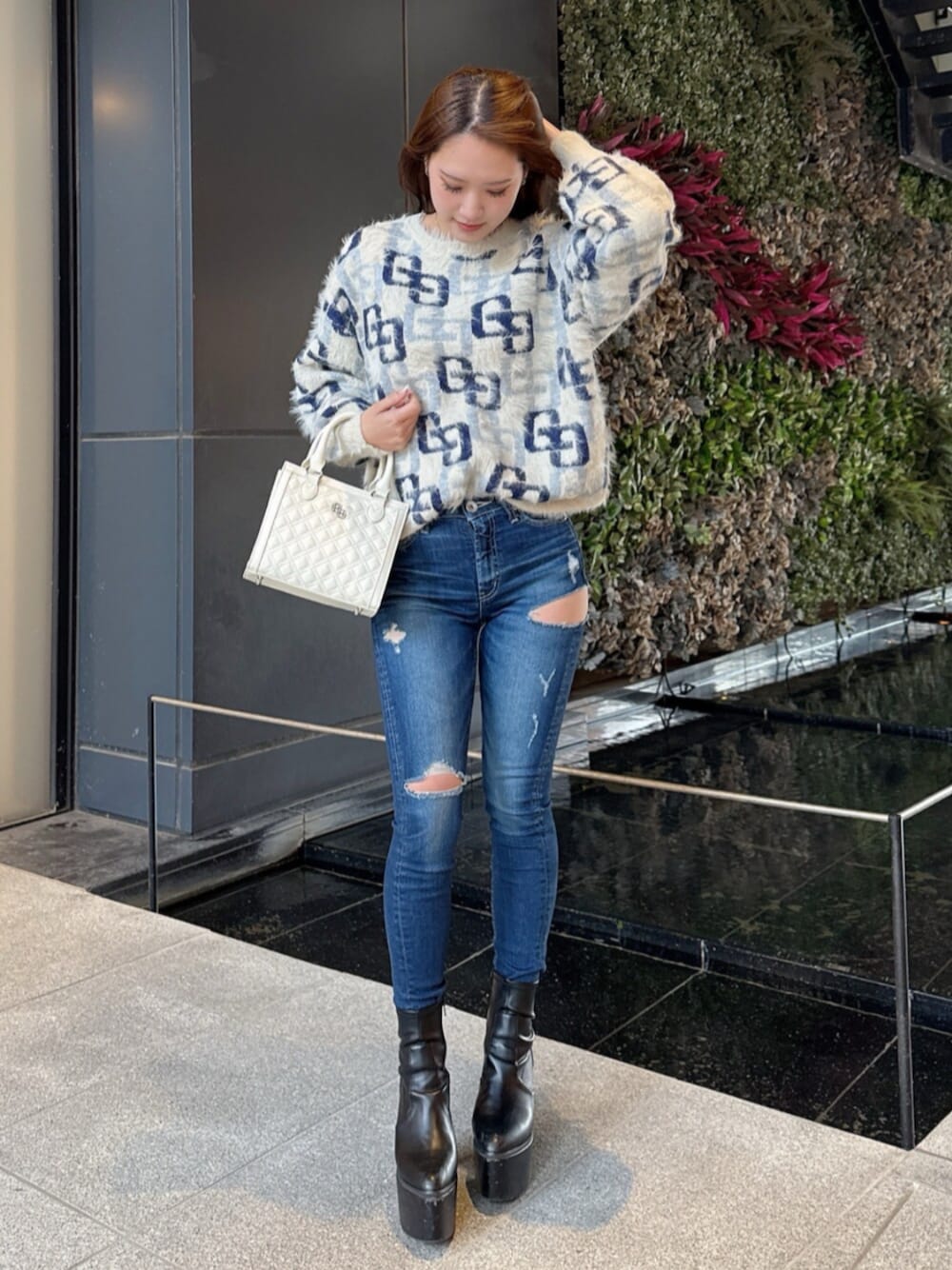 ブラック系のブーツ、ホワイト系のニット/セーター、ブルー系のデニムパンツを着用したレディースの冬コーディネートの1枚目の写真