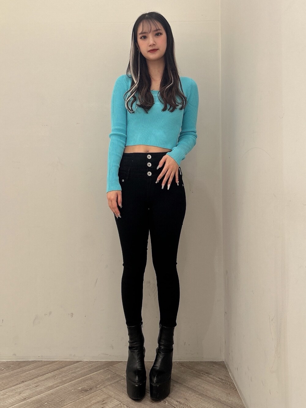 ブルー系のニット/セーター、ブラック系のデニムパンツ、ブラック系のブーツを着用したレディースの冬コーディネートの1枚目の写真