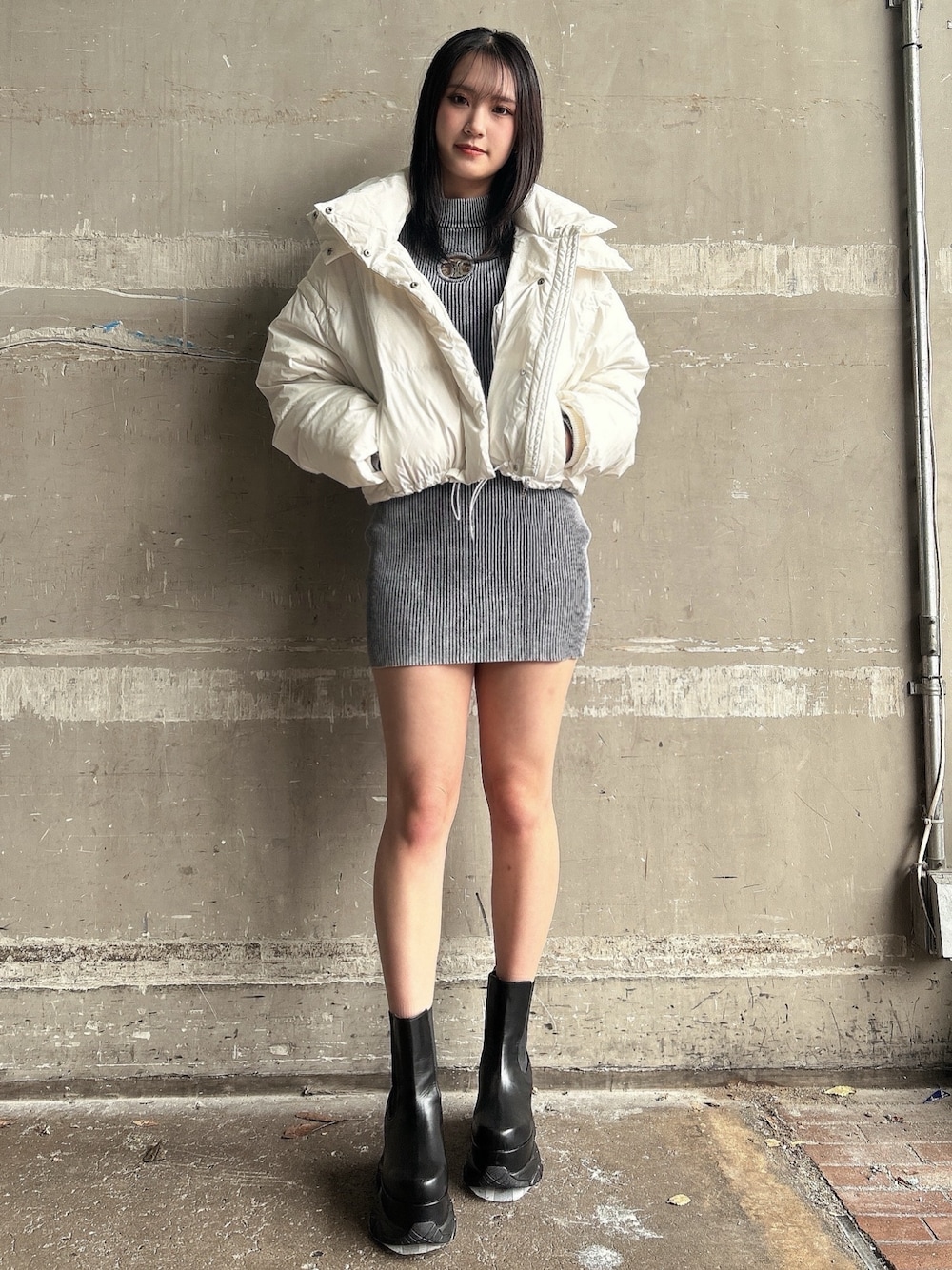 ブルー系のワンピース、ホワイト系のダウンジャケット/コート、ブラック系のブーツを着用したレディースの冬コーディネートの1枚目の写真