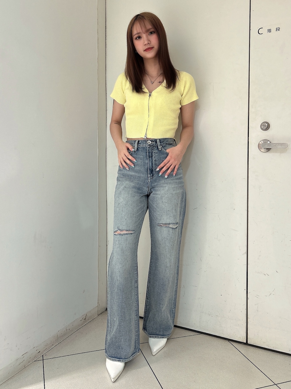 イエロー系のニット/セーター、ブルー系のデニムパンツ、ホワイト系のパンプスを着用したレディースの春コーディネートの1枚目の写真