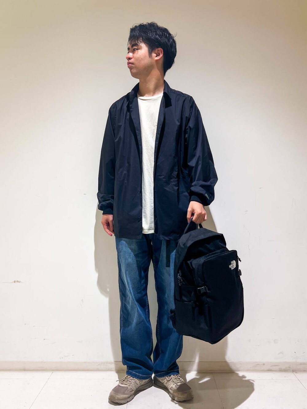 グリーン系のスニーカー、ブルー系のデニムパンツ、ブラック系のシャツ/ブラウスを着用したメンズの秋コーディネートの1枚目の写真