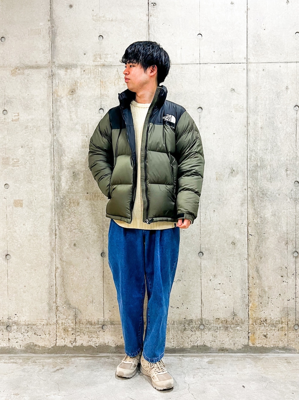 グリーン系のダウンジャケット/コート、ベージュ系のニット/セーター、ブルー系のその他パンツを着用したメンズの冬コーディネートの1枚目の写真