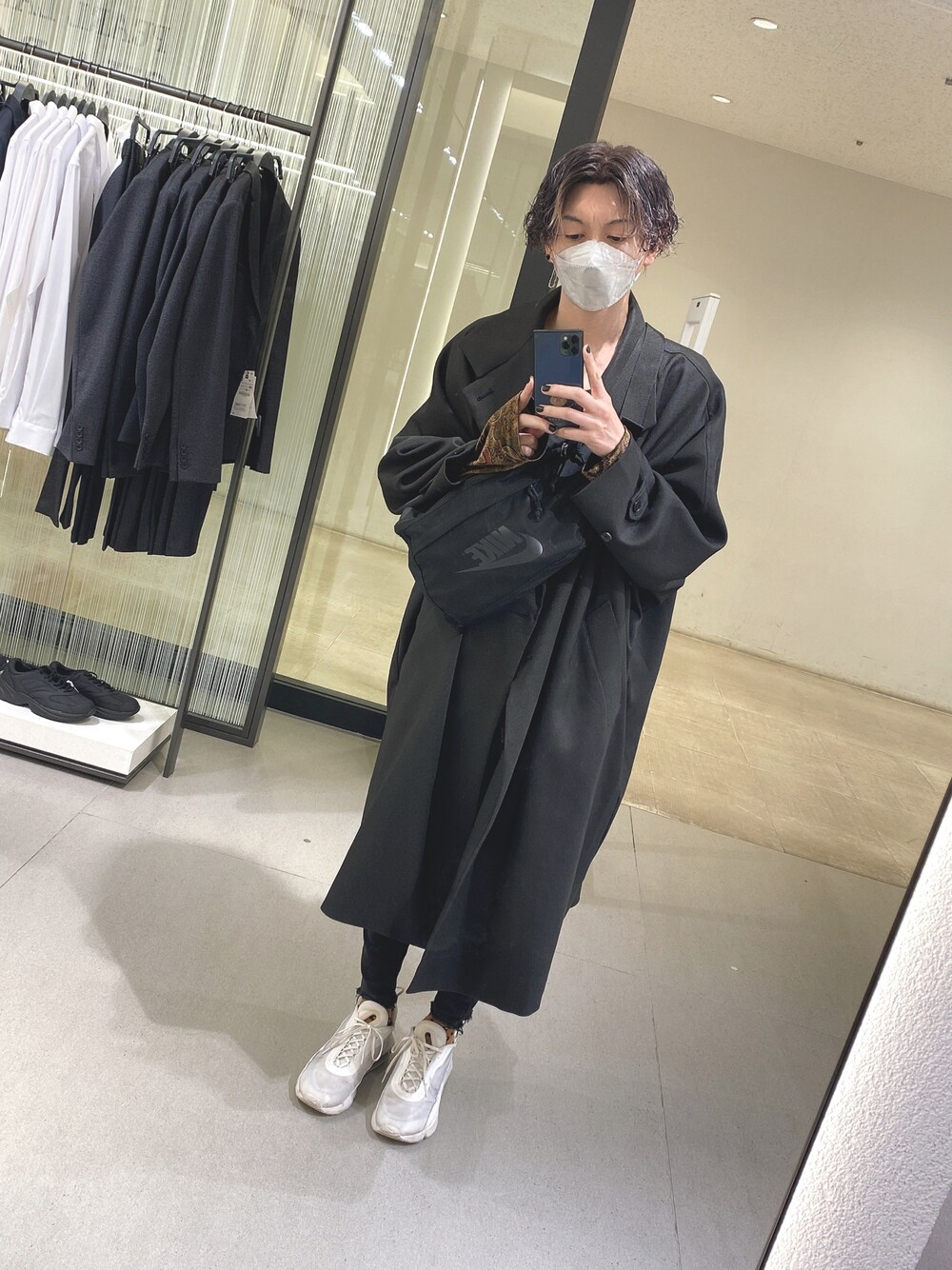 ホワイト系のスニーカー、ブラック系のチェスターコートを着用したメンズの秋コーディネートの1枚目の写真