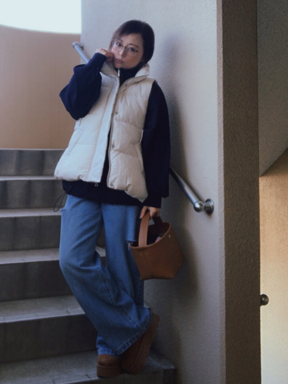 ホワイト系のダウンベスト、ブルー系のその他アウター、ブルー系のデニムパンツを着用したレディースの冬コーディネートの1枚目の写真