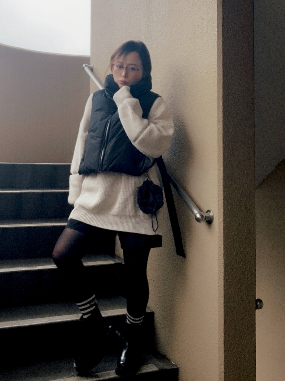 ブラック系のベスト、ホワイト系のニット/セーター、ブラック系のチノパンツを着用したレディースの冬コーディネートの1枚目の写真