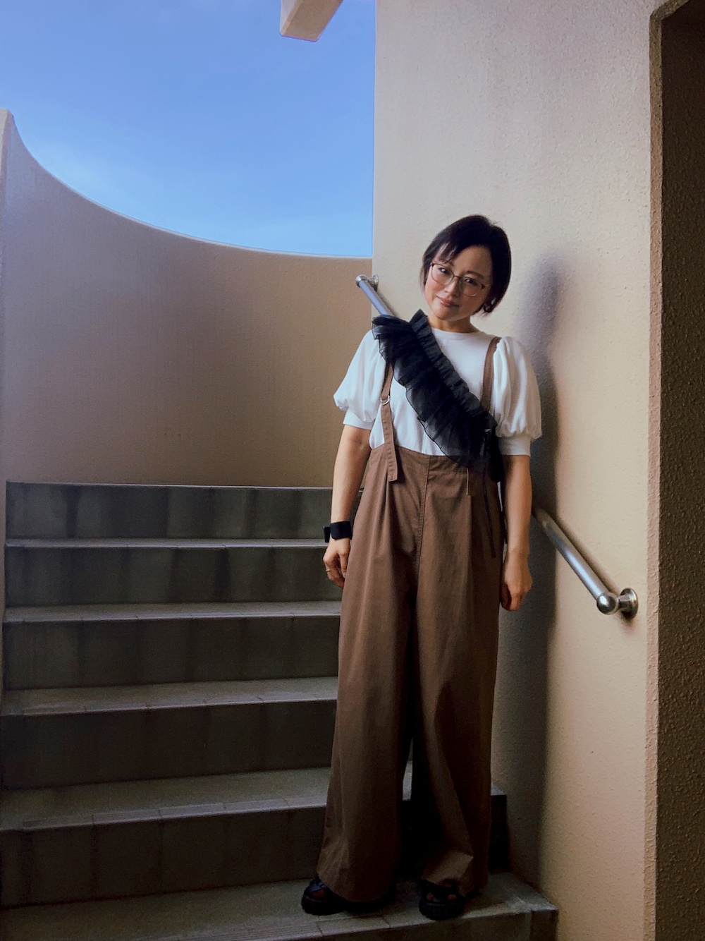 ホワイト系のTシャツ/カットソー、ブラウン系のその他パンツ、ブラック系のサンダルを着用したレディースの秋コーディネートの1枚目の写真