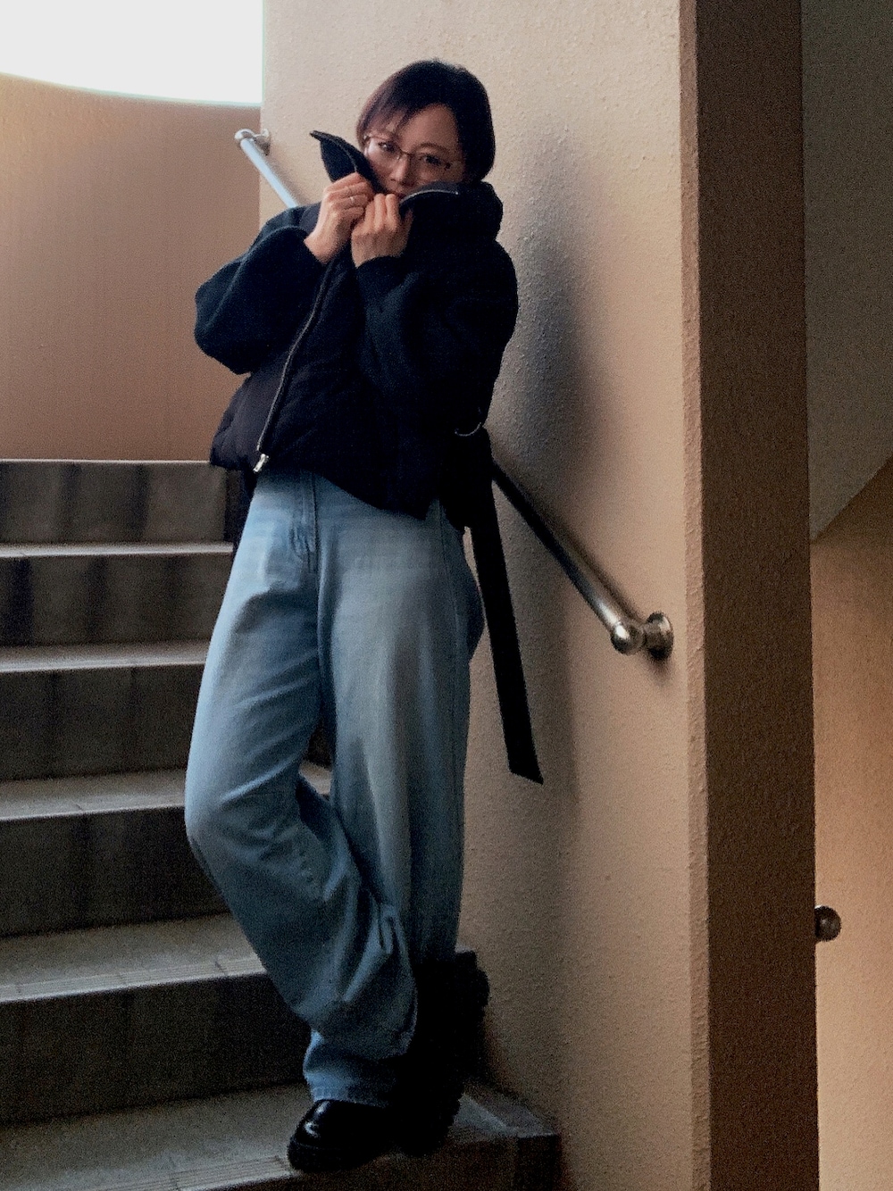 ブラック系のベスト、ブラック系のニット/セーター、ブルー系のデニムパンツを着用したレディースの冬コーディネートの1枚目の写真