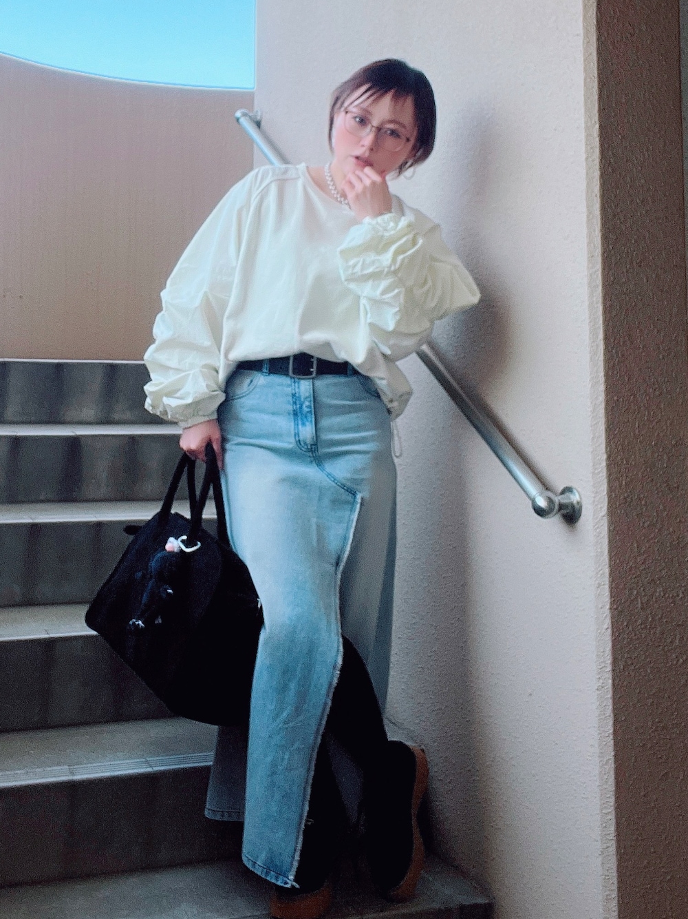 ホワイト系のスウェット、ブルー系のデニムスカート、ブラック系のスニーカーを着用したレディースの春コーディネートの1枚目の写真