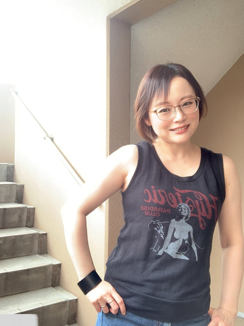 ブラック系のタンクトップ、ブルー系のデニムパンツ、ブラック系のサンダルを着用したレディースの夏コーディネートの1枚目の写真