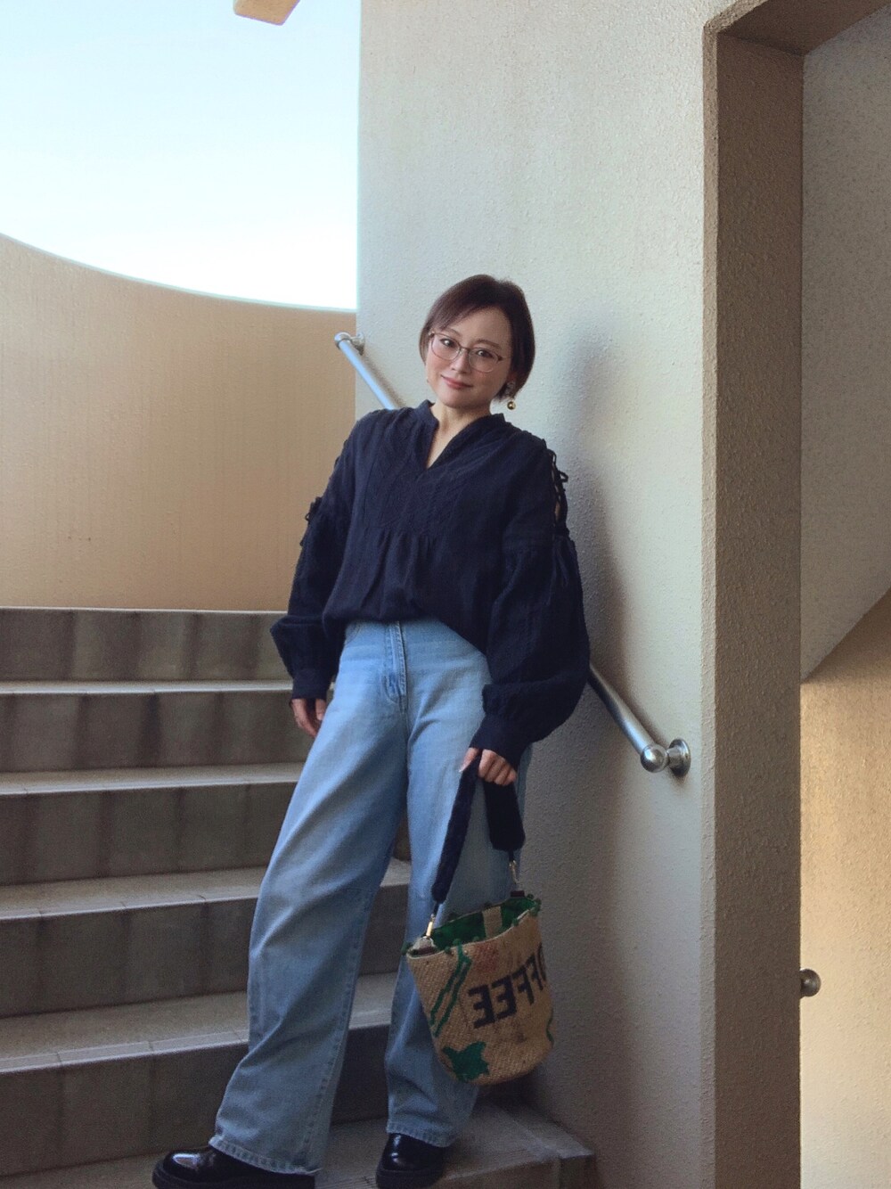 ブラック系のシャツ/ブラウス、ブルー系のデニムパンツ、ブラック系のブーツを着用したレディースの秋コーディネートの1枚目の写真
