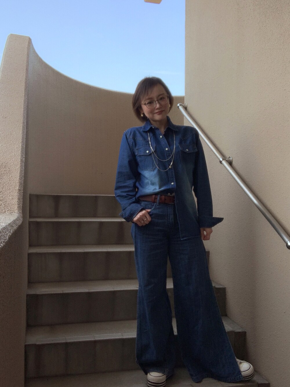 ブルー系のシャツ/ブラウス、ブルー系のデニムパンツ、ホワイト系のスニーカーを着用したレディースの春コーディネートの1枚目の写真