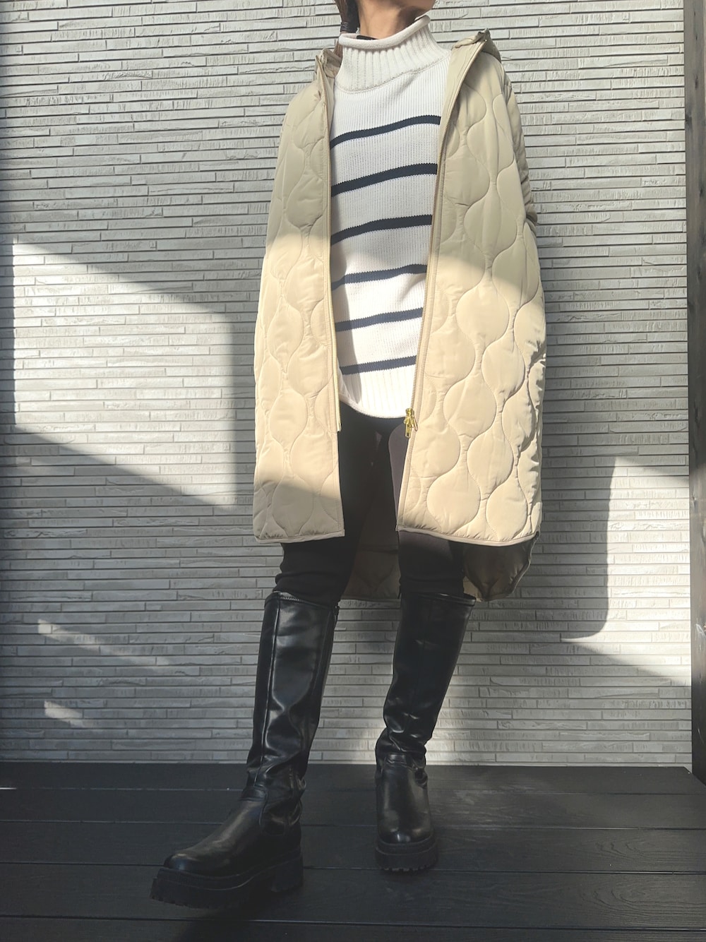 ベージュ系のその他アウター、ブラック系のブーツ、ブラック系のトップスを着用したレディースの冬コーディネートの1枚目の写真