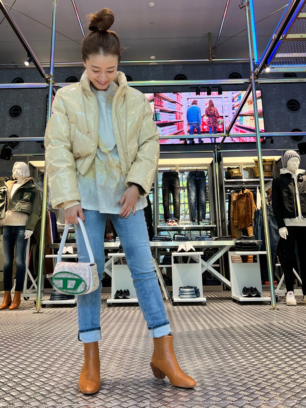 ブルー系のデニムパンツ、グリーン系のショルダーバッグ、ブラウン系のブーツを着用したレディースの秋コーディネートの1枚目の写真