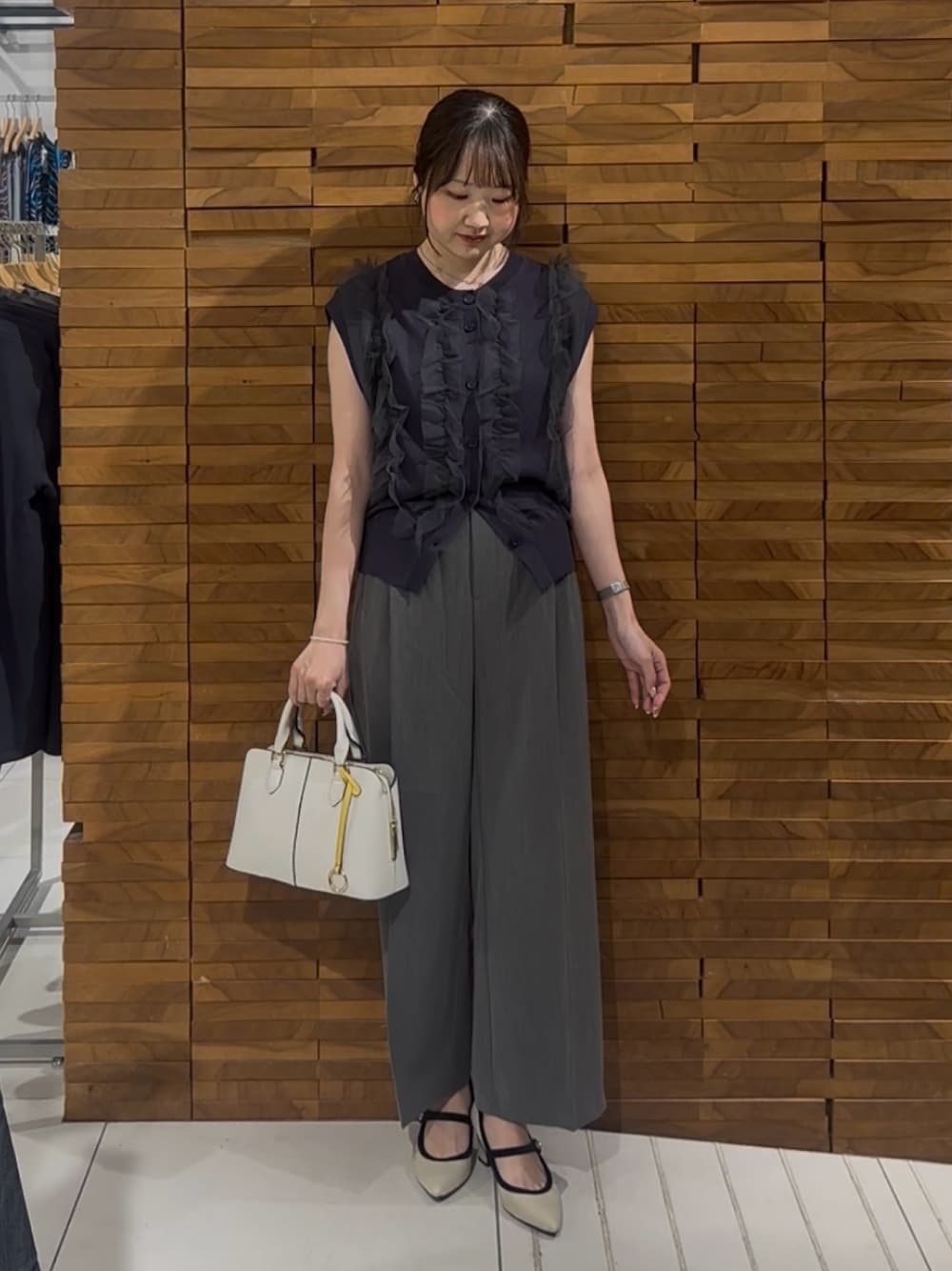 グレー系のベスト、グレー系のその他パンツ、ホワイト系のハンドバッグを着用したレディースの春コーディネートの1枚目の写真