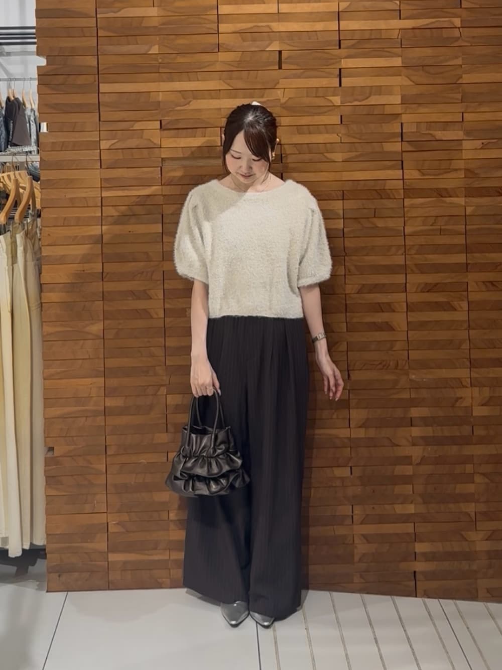 ホワイト系のニット/セーター、ブラウン系のその他パンツ、ゴールド系のハンドバッグを着用したレディースの秋コーディネートの1枚目の写真