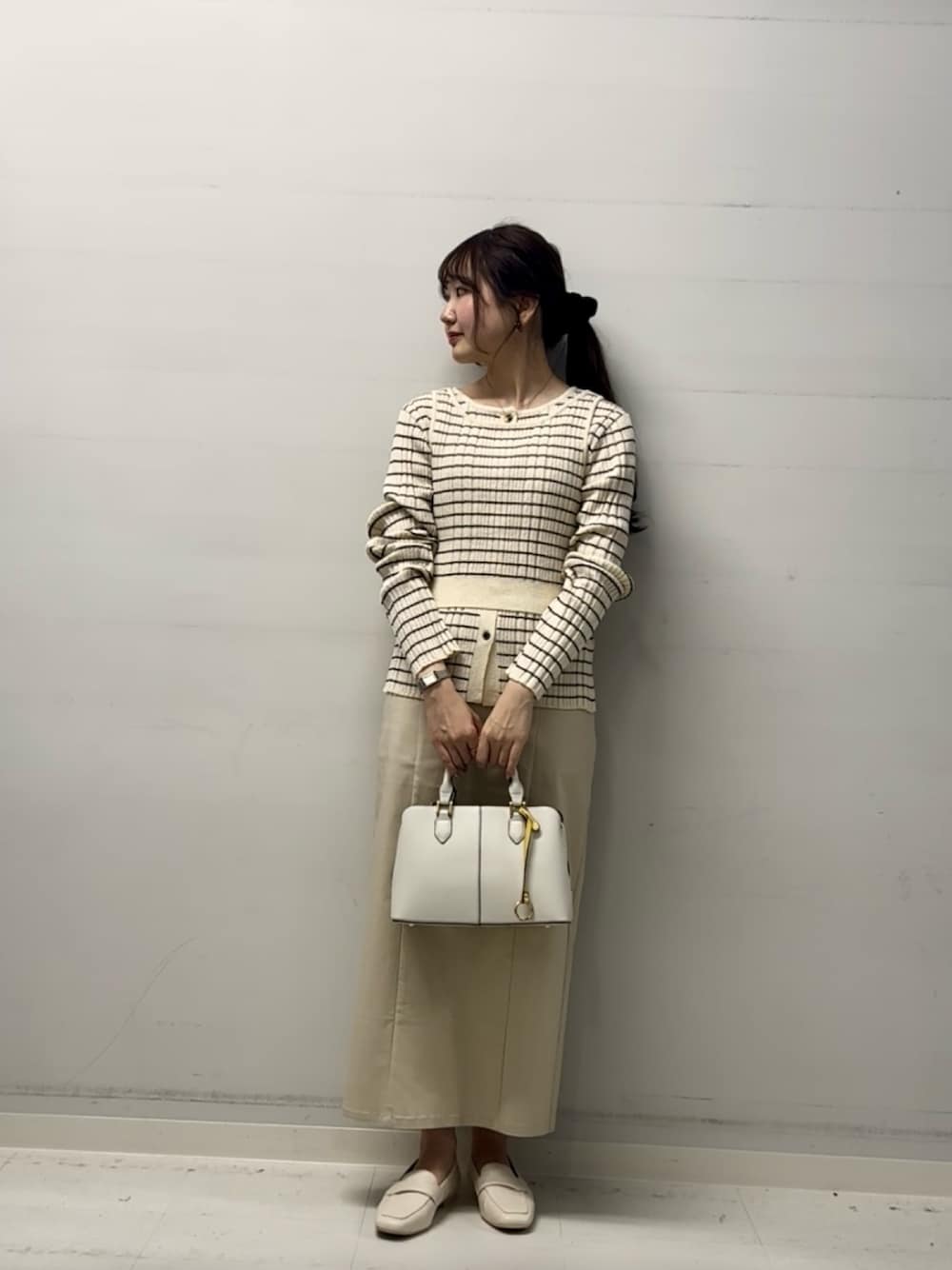 ベージュ系のスカート、ホワイト系のニット/セーター、ベージュ系のローファーを着用したレディースの冬コーディネートの1枚目の写真