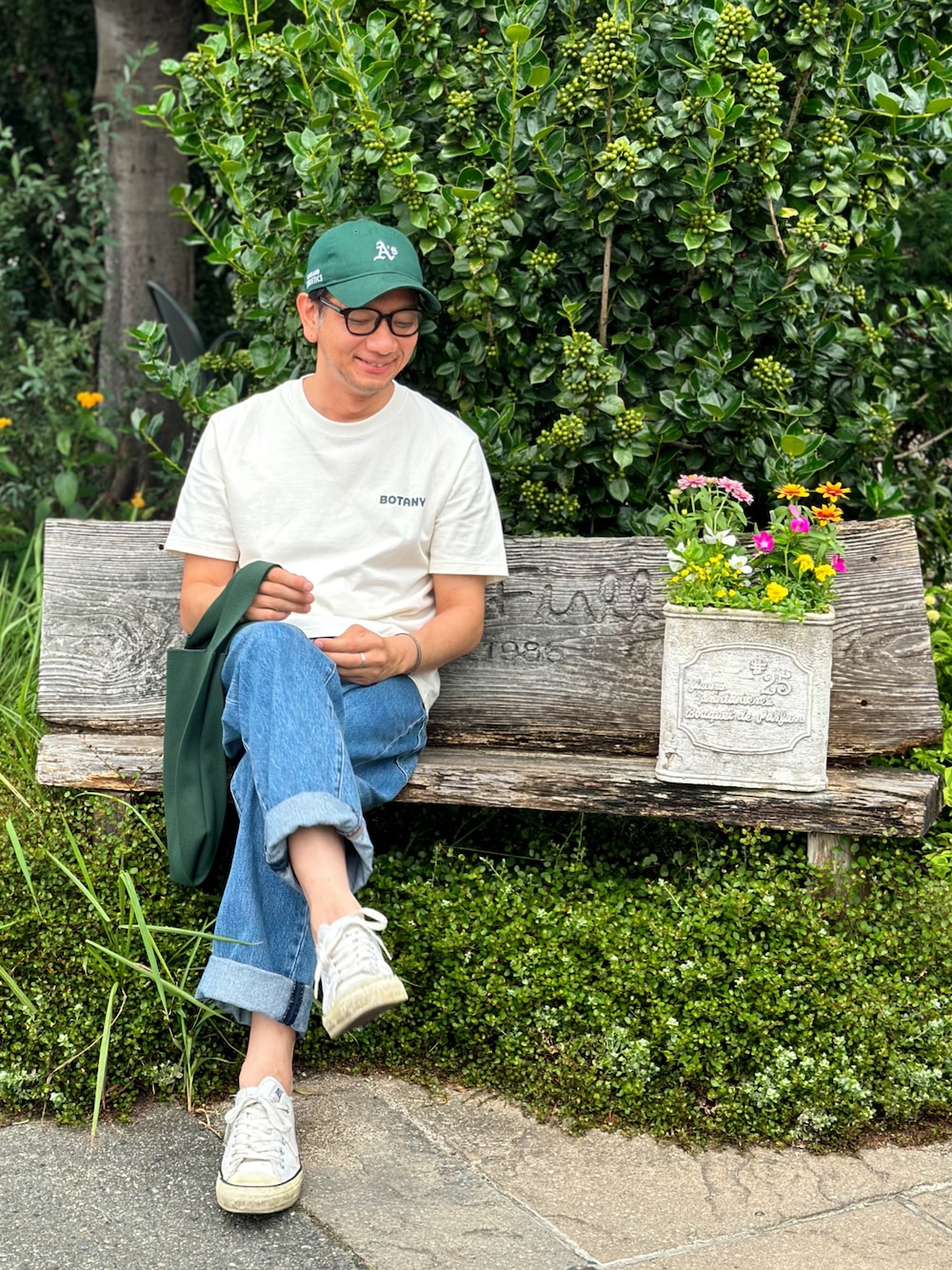 ホワイト系のスニーカー、ブルー系のデニムパンツ、グリーン系のエコバッグ/サブバッグを着用したメンズの夏コーディネートの1枚目の写真