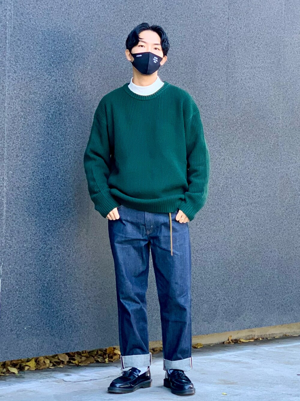 グリーン系のニット/セーター、ホワイト系のTシャツ/カットソー、ブルー系のデニムパンツを着用したメンズの秋コーディネートの1枚目の写真