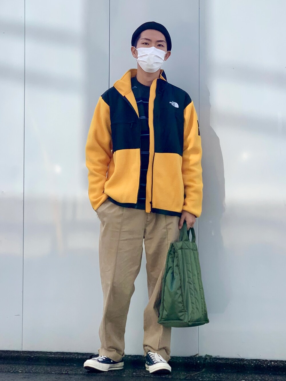 イエロー系のブルゾン、ブルー系のTシャツ/カットソー、ベージュ系のチノパンツを着用したメンズの秋コーディネートの1枚目の写真