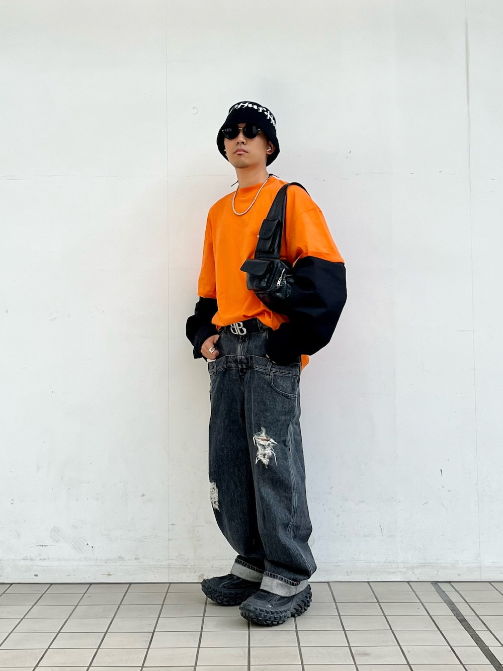 「おしゃれさんと繋がりたい、ロゴT、ロンT、オレンジ、レイヤードスタイル、レイヤード、デニム、デニムパンツ、ダブルウエスト、ストリート、オーバーサイズ、スリングバッグ、春服」｜「JW Andersonのアイテム（デニムパンツ、グレー系）」を使った、macky☺︎さん（メンズ・172cm）の春コーディネートの1枚目の写真