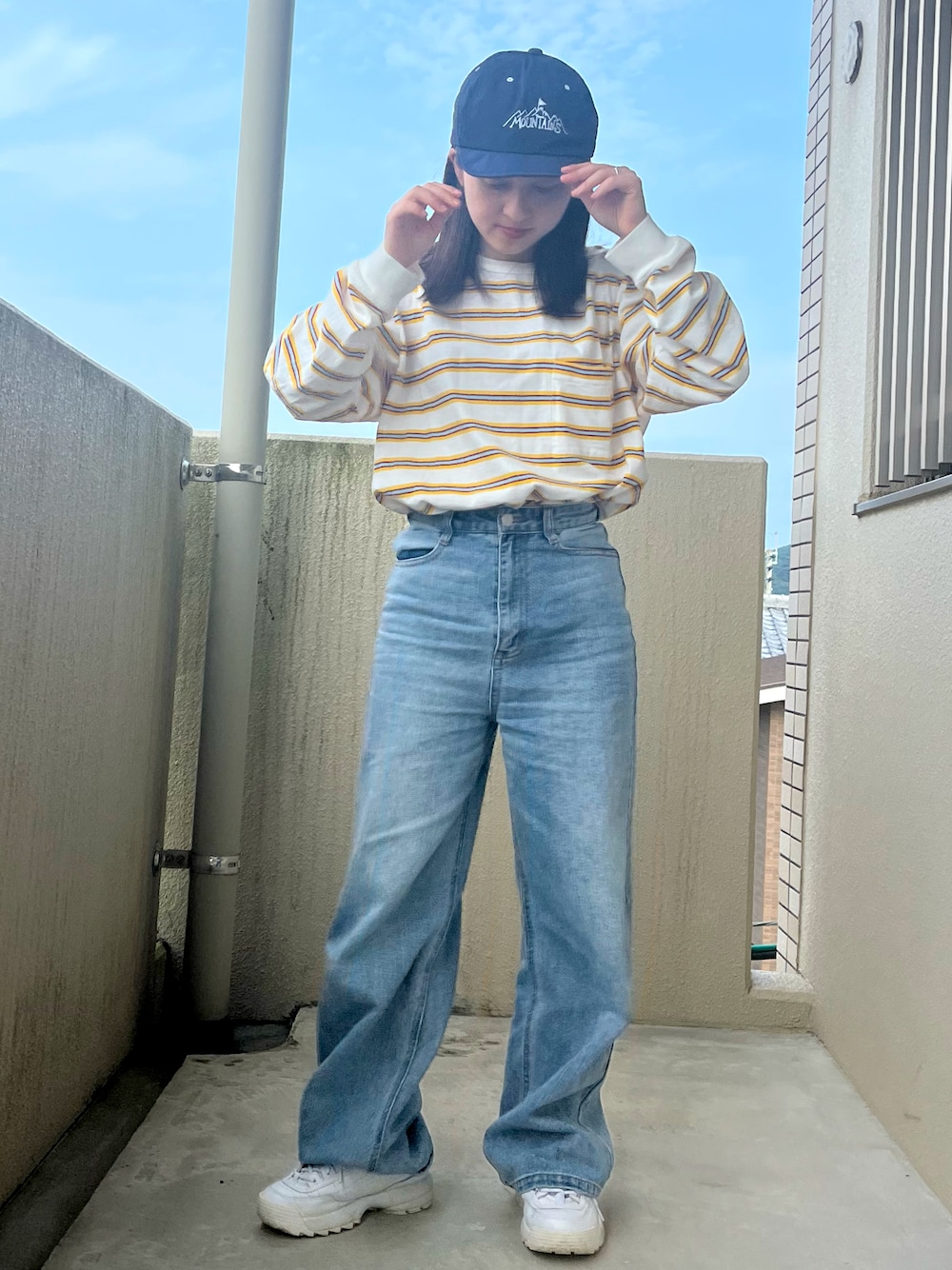 ホワイト系のトップス、ブルー系のデニムパンツ、ホワイト系のスニーカーを着用したレディースの秋コーディネートの1枚目の写真