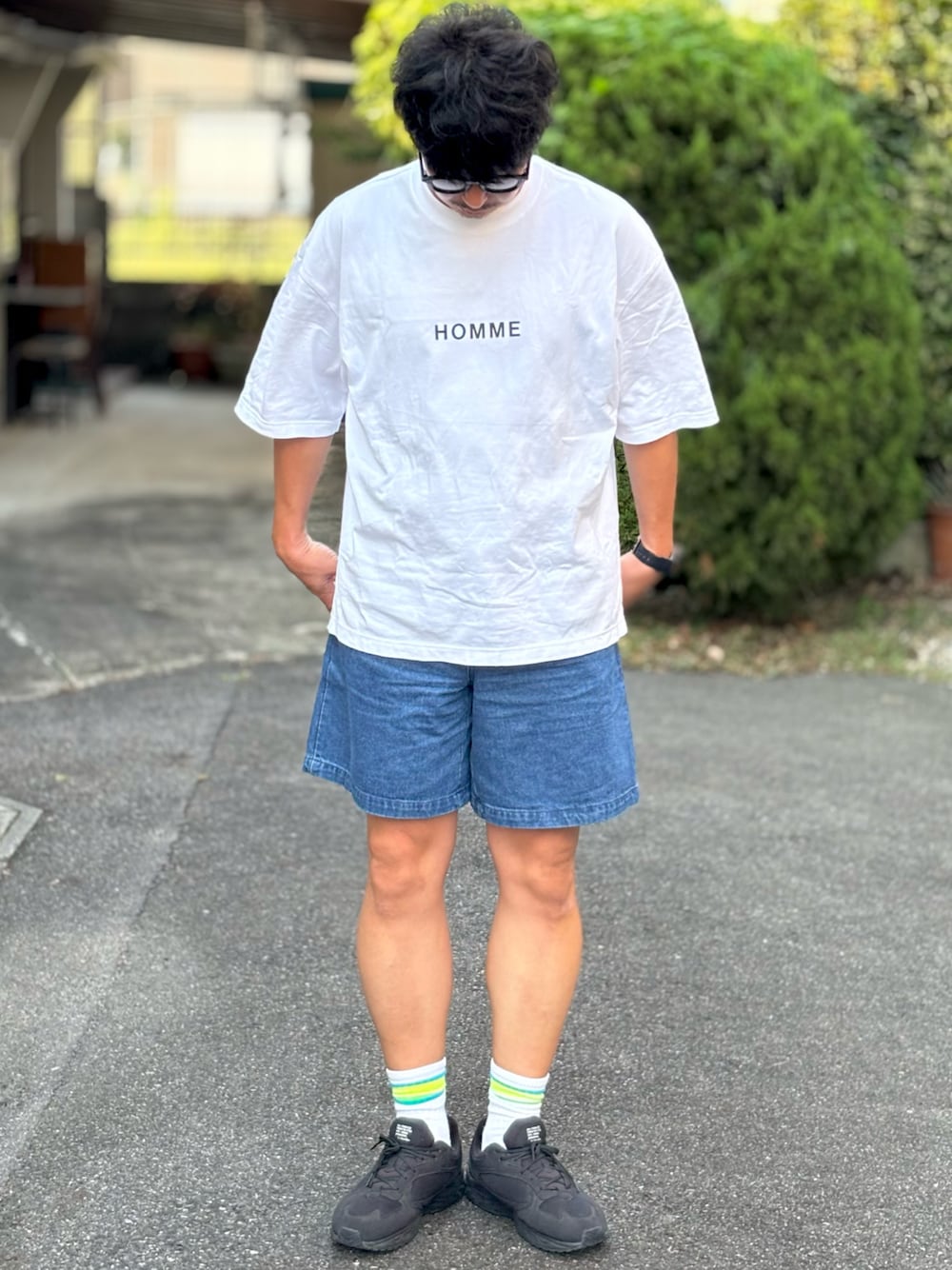 ブラック系のスニーカー、ホワイト系のTシャツ/カットソー、ブルー系のデニムパンツを着用したメンズの夏コーディネートの1枚目の写真
