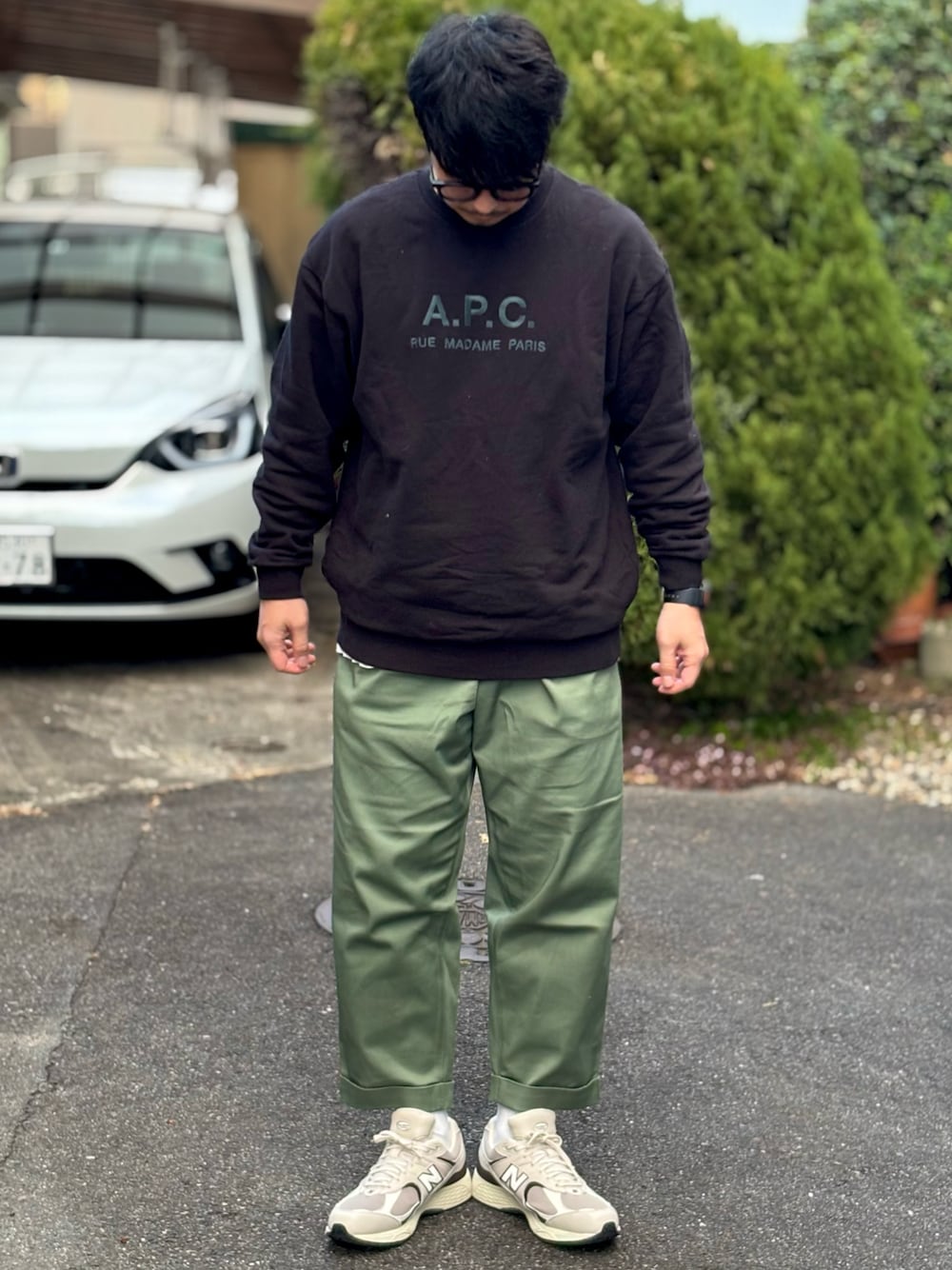 ブラック系のスウェット、グリーン系のチノパンツ、ベージュ系のスニーカーを着用したメンズの冬コーディネートの1枚目の写真
