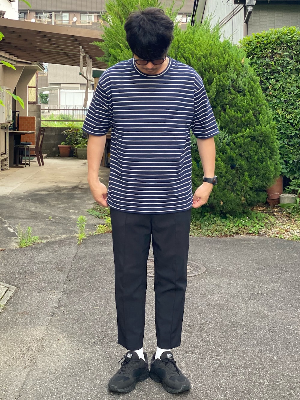 ブルー系のTシャツ/カットソー、ブラック系のスラックス、ブラック系のスニーカーを着用したメンズの夏コーディネートの1枚目の写真